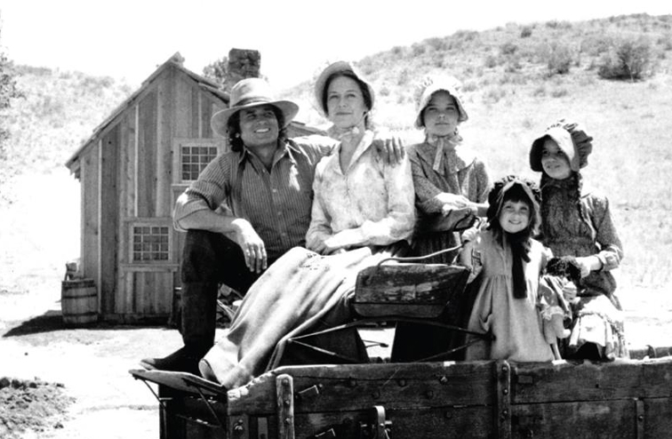 A black and white photo of Melissa Gilbert and cast on the set of Little House on the Prairie.
