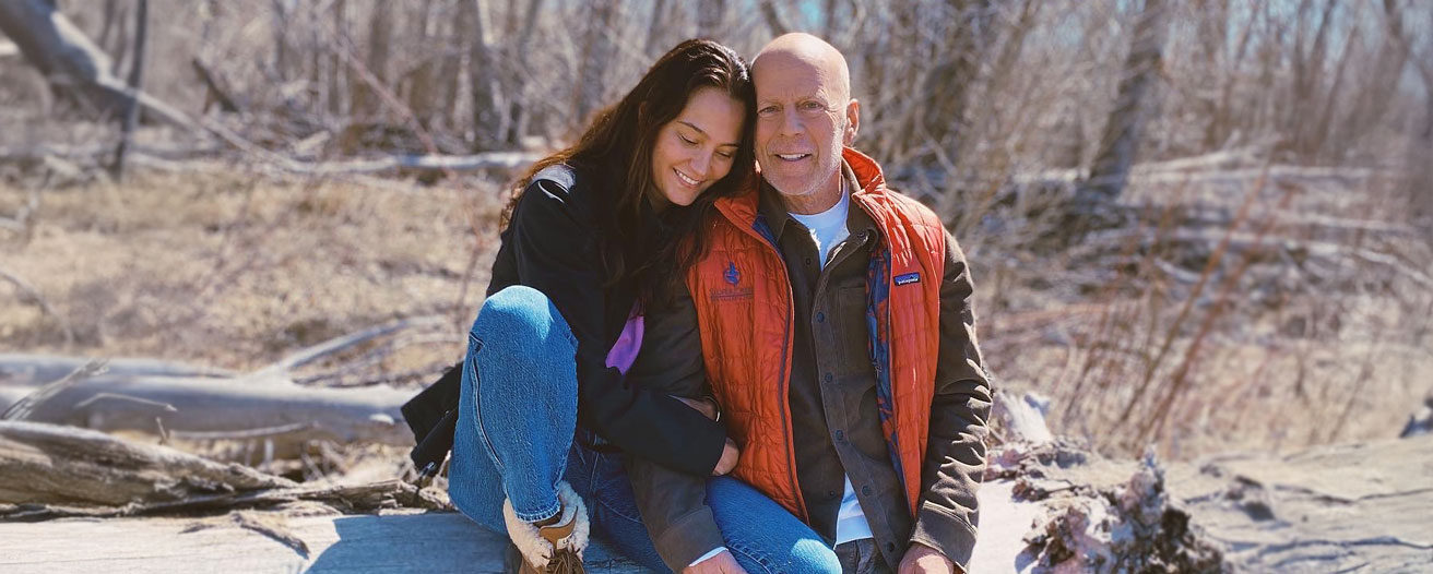 Emma Heming Willis and Bruce Willis seated together outside in a natural setting.