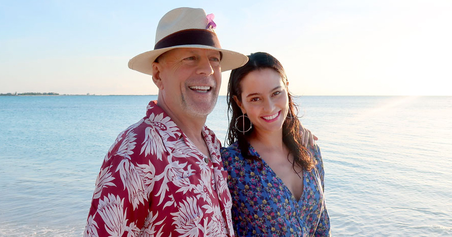Emma Heming Willis and Bruce Willis walk along a beach shoreline together.