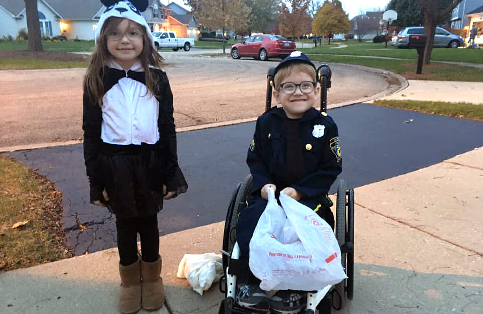 Henry Watts, who was born with spina bifida, dressed as a police officer for Halloween alongside another child in costume.